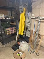 Photo showing hanging Orvis vinyl waders in gray and yellow fishing gear items with tackle boxes and a rack nearby.