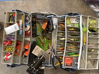 Opened Flambeau tackle box displaying a variety of colorful fishing lures, tools, and accessories arranged in multiple compartments.
