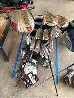 Overall view of golf clubs set in bag with covers and boxed golf balls.