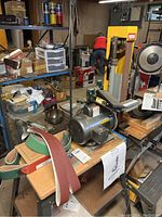 Overview of belt sander with motor, belts and manual on tabletop