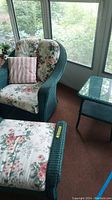 Full view of green wicker armchair, ottoman and side table in sunroom