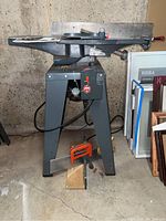 Full side view of the ShopSmith 4 inch jointer mounted on a metal motorized stand in a basement environment