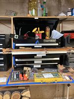 Overview of the Craftsman metal toolbox with drawers, several hand tools including saws and level on the work surface.