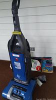 Full view of upright Hoover WindTunnel vacuum with extra bags placed beside it.