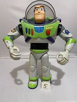 Front view of 12 inch Buzz Lightyear figure in green, white, and purple space suit, helmet open, showing detailed facial features and buttons.