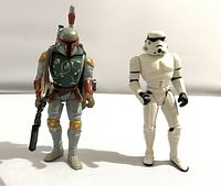 Photo of both Star Wars action figures: Boba Fett and Stormtrooper side by side on a plain background.