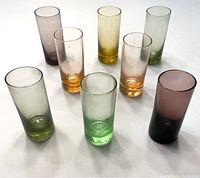 Photo showing eight assorted colored shot glasses arranged upright, showcasing colors and shape.