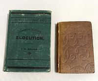 Two antique books: one brown embossed hardcover book with spine wear, the other a green softcover book titled 'Common School Elocution' by J.H. Brown