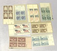 Front view showing eight blocks of uncanceled US stamps in various colors and themes arranged on a light surface in protective sleeves.