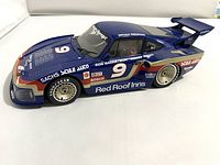 Side view of blue Porsche 935 car model with detailed racing decals and number 9 on hood and side, showing intact paint and decals