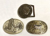 Frontside of the three belt buckles showing eagle, covered wagon, and penny design