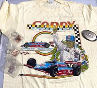 Photo of Gordon Johncock T-shirt with colorful racing print and visible keyrings and belt buckle around it.