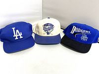 Front view of the three baseball caps showing different Dodgers logos and colors.