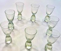 Set of eight clear liqueur/shot glasses arranged in a circle on a white surface, showing the bubble design in bases and tapered bowls.