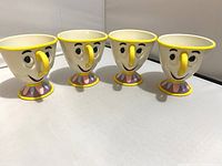 Four plastic Chip character cups shown from front with faces and yellow features