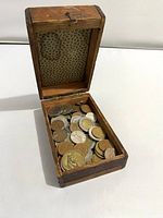 Closed wooden box showing interior patterned lining and variety of coins inside