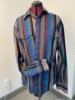 Front view of the Wrangler cowboy cut long sleeve striped shirt on a dress form showing multicolor vertical stripes and buttoned chest pockets.