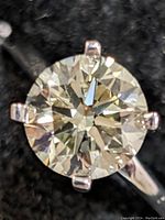 Close-up top view of round brilliant-cut diamond showing faceting and prongs.