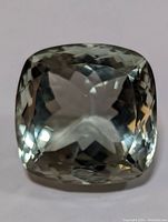 Top view of a single cushion cut genuine green amethyst gemstone showing clarity and color.