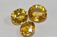 Three yellow sapphire gemstones arranged together on white background.