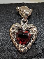 Front view of the heart-shaped garnet pendant set in textured sterling silver setting on black background.