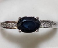 Close-up of sapphire ring front showing oval sapphire and clear stones along band.