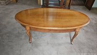 Photo of the wooden oval coffee table showing tabletop surface and carved legs.