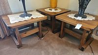 Three wooden end tables positioned closely together on carpet, each with square tops and wooden construction. Visible scratches and worn finish on tables.