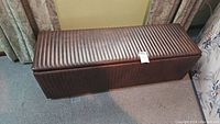 Front and top view of brown leather storage bench with ribbed pattern on top and sides, closed lid.