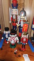 Group of six nutcracker figurines on wooden floor, showing sizes and designs