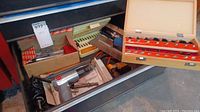 Drawer with screwdriver, multiple boxes of bits, pneumatic air tool, and other hand tools visible.
