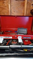 Photo capturing the open red Craftsman metal tool chest filled with various hand tools, screwdriver sets, and a Haupt label visible.