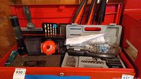Wide view of the tool lot showing flashlight, drill bits, laser level, safety glasses, and screwdriver set in plastic cases along with other tools