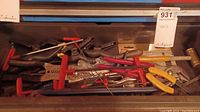 Top view of a box of hand tools showing multiple Allen wrenches, wire cutters, wrenches, a hammer, saw, and blades.