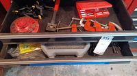 Second drawer showing assorted drill bits, socket set in red case, metal bar clamp, and additional clamp tools.