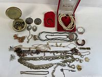 Overview photo showing assorted jewelry including multiple necklaces, earrings, brooches, and bracelets laid out on a white surface