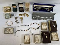 Wide view of assorted jewelry including necklaces, pendants, earrings and chains arranged on a flat white surface.