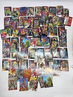 Overview photo showing a wide assortment of trading cards from Valiant and Marvel Comics spread out on a flat surface. Includes various comic character art and vibrant colors.
