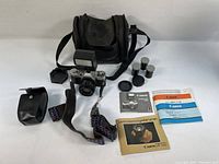 Overview of camera, flash, case, film canisters, lens caps, and manuals arranged on surface