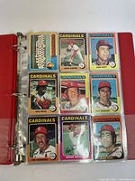 Photo showing 9 MLB baseball player cards of St. Louis Cardinals in plastic sleeves of binder.