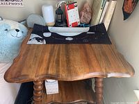 Top view of medium brown antique wooden side table surface with shaped edge and dark wood grain.