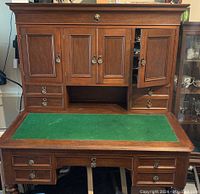 Frontal view of desk with closed upper cabinets, drawers and green felt top