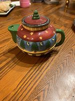 Side view of the colorful ceramic teapot showing the painted design and lid.