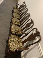 Six Ethan Allen armchairs lined up, showing dark wood frames with floral upholstered seats.