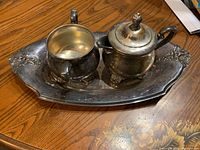 Silver coffee serving set on wooden table: tray, two coffee cups, sugar pot with lid