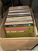 Photo of box with stacked vinyl record albums showing 'My Fair Lady' album cover on top.