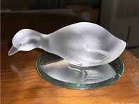Side view of clear frosted crystal duck figurine on round glass mirror base