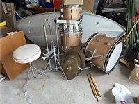 Overview of sparkle gold drums, hardware stands, cymbals, cowbell, stool and sticks