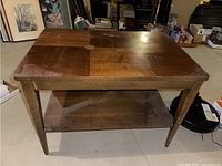 Front view of the wooden Mersman side table showing tapered legs and lower shelf.
