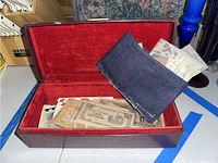 Wooden box containing assorted paper money and a fabric pouch